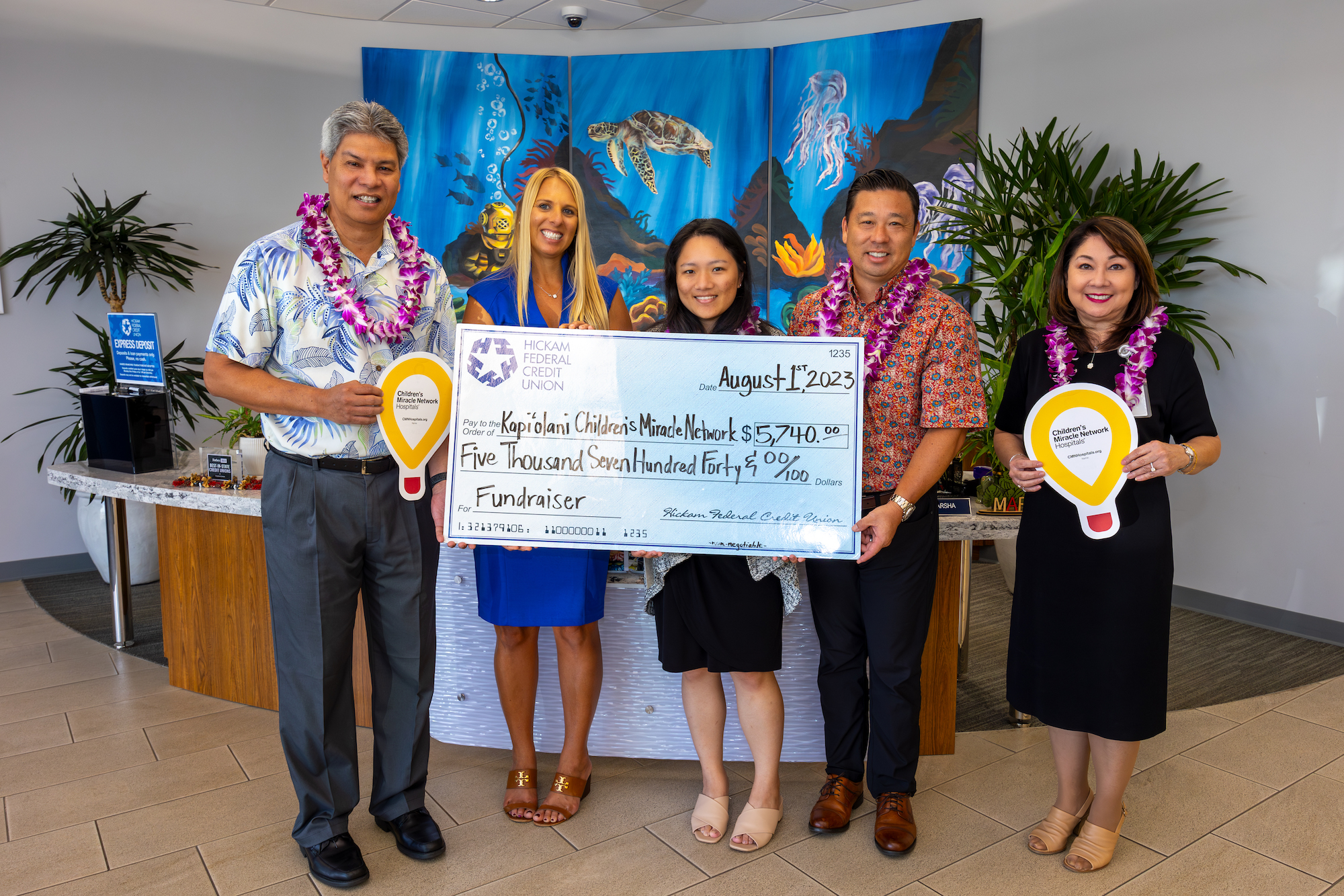 Hickam FCU staff poses with Amanda Price of Hawaii Pacific Health while holding a giant check.