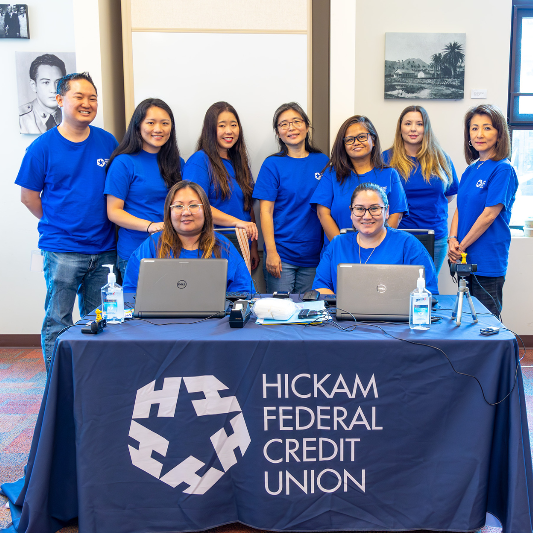 A group of Hickam FCU staff volunteers pose in front of a table