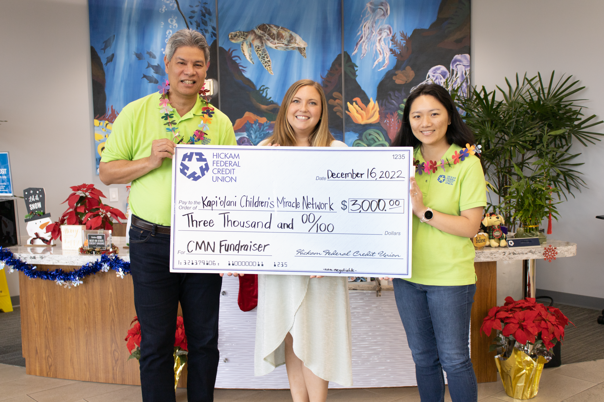 Scott Kaulukukui poses with Colette Forcier of Kapi'olani Children's Miracle Network and a staff member with donation check
